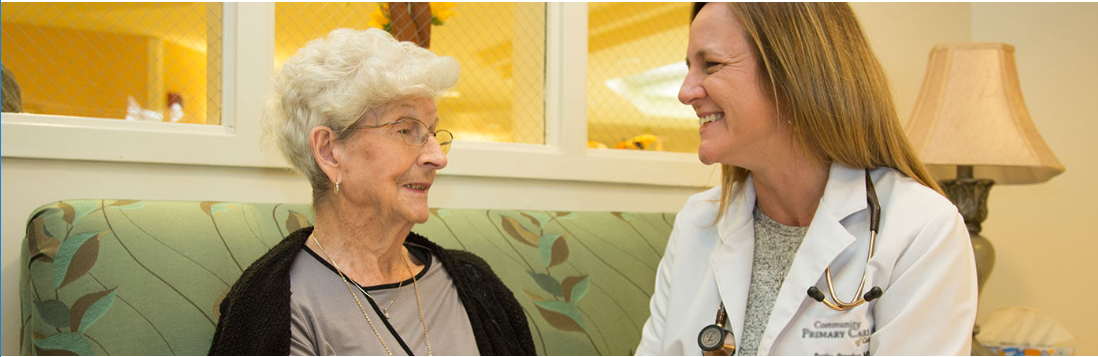 Image of an associate smiling on a couch with a patient at a health center