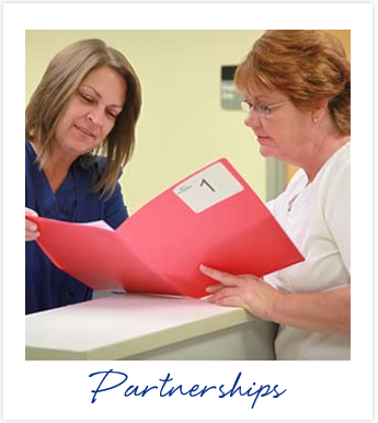 Two associates at nurses desk looking at patient file above the word 'Partnerships'